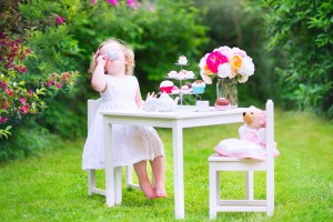 Toddler girl playing tea party with a doll