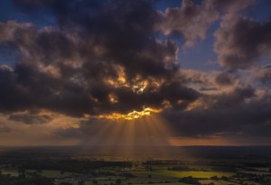 Crepuscular rays of sunlight shine onto fields in Dorset